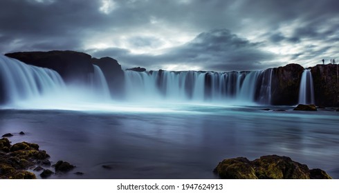 Powerful streams of the waterfall cascading into the reservoir. Dramatic sky. Long exposure. Godafoss waterfall, Iceland. 