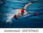 Powerful strokes. Freestyle swimming type. Young man, swimmer in motion training in swimming pool. Concept of professional sport, health, endurance, strength, active lifestyle