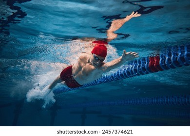 Powerful strokes. Freestyle swimming type. Young man, swimmer in motion training in swimming pool. Concept of professional sport, health, endurance, strength, active lifestyle - Powered by Shutterstock