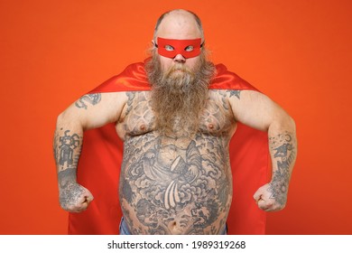 Powerful Strong Fat Chubby Overweight Tattooed Bearded Big Belly Man 30s Dressed In Red Superhero Suit Have Supernatural Abilities Isolated On Orange Backround Studio Portrait. Real Heroes Defend You.