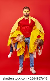 Powerful Strong Super Man Holding Crazy Kids In Hands, Trying To Calm Down