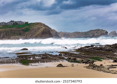 Powerful surf waves with a foam crest. Dramatic stormy sky. Noon on the beach of Playa di Arnia, Spain. Cantabria. Windy stormy day on the Atlantic coast.  - Powered by Shutterstock