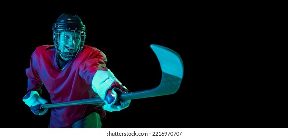 Powerful throw. Male ice hockey player in sports uniform and protective equipment in action over dark background in neon light. Sport, power, challenges, achievement, goals concept - Shutterstock ID 2216970707