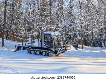 A powerful tractor thoroughly clears the ski slope of snow, preparing it for winter sports.