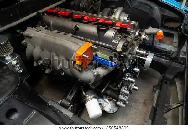 Powerful tuned gasoline engine with\
a turbocharger and a charger in the engine compartment of the car\
with an open hood in a car repair and improvement\
workshop.
