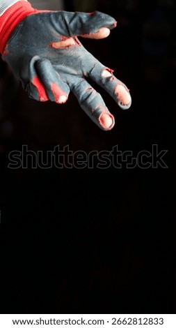 A powerful vertical shot capturing a damaged glove on a hand, with two fingers extended against a stark black background. This image is a poignant representation of poverty and hardship.