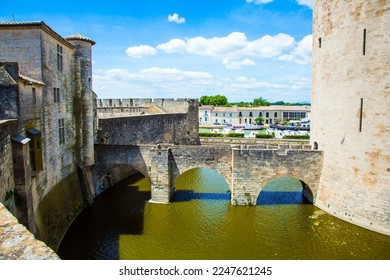 Powerful walls and a moat with water surround the ancient city of Aigues-Mortes. Mediterranean coast of France. The concept of active, historical and photo tourism