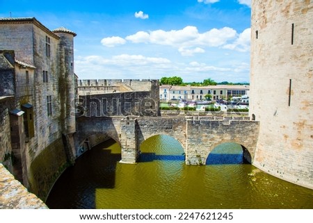 Powerful walls and a moat with water surround the ancient city of Aigues-Mortes. Mediterranean coast of France. The concept of active, historical and photo tourism