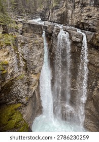 Powerful waterfall cascading down high rocky cliffs into a deep canyon.