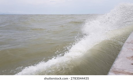 A powerful wave crashes against a solid barrier, showcasing the raw energy and force of nature's untamed power