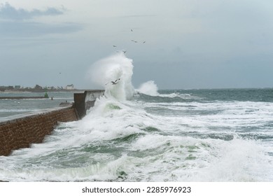 Powerful waves crash on a pier in Lesconil in Brittany - Powered by Shutterstock