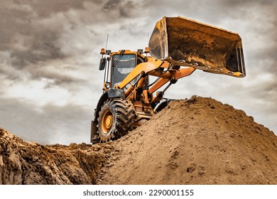 Powerful wheel loader or bulldozer working on a quarry or construction site. Loader with a full bucket of sand against the sky. Powerful modern equipment for earthworks