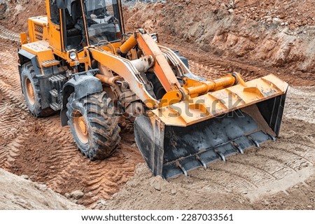 Powerful wheel loader or bulldozer working on a quarry or construction site. Close-up of earthworks. Powerful modern equipment for earthworks