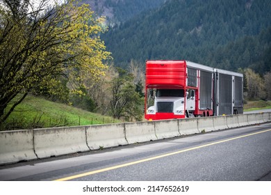 Powerful white big rig car hauler semi truck with covered protected red semi trailer with black tent sides for luxury and exotic cars transportation running on the highway road in Columbia Gorge