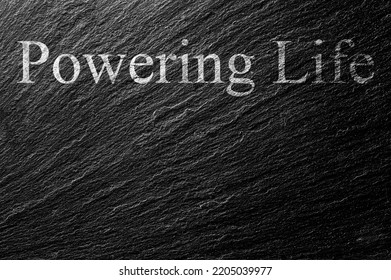 Powering Life Chalk Text On Black Stone Slab