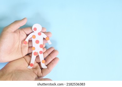 Pox disease such as monkeypox, smallpox and chicken pox care, prevention and protection concept. Hand holding human body cutout with red rash sores and blisters on skin in dark black background.