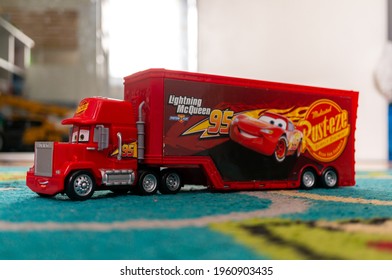 POZNA, POLAND - Apr 06, 2021: Red Toy Model Mack Truck With Trailer Of The Disney Pixar Cars Movie On A Carpet Floor In A Child Room 