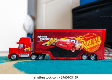 POZNA, POLAND - Apr 06, 2021: Red Toy Model Mack Truck With Trailer Of The Disney Pixar Cars Movie On A Carpet Floor In A Child Room 