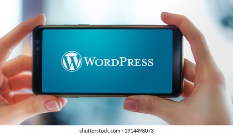POZNAN, POL - FEB 6, 2021: Hands holding smartphone displaying logo of WordPress, a free and open-source content management system (CMS) written in PHP and paired with a MySQL or MariaDB database