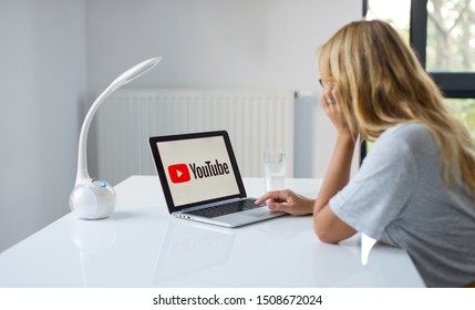 Poznan, Poland, 3.09.2019. Young Woman Using Laptop With YouTube Logo In The Screen Seeting At The Office Desk. A Girl In Office Watching You Tube. 