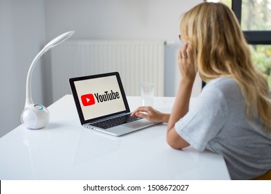 Poznan, Poland, 3.09.2019. Young Woman Using Laptop With YouTube Logo In The Screen Seeting At The Office Desk. A Girl In Office Watching You Tube. 