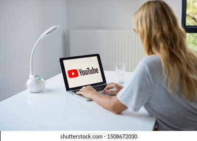 Poznan, Poland, 3.09.2019. Young Woman Using Laptop With YouTube Logo In The Screen Seeting At The Office Desk. A Girl In Office Watching You Tube. 