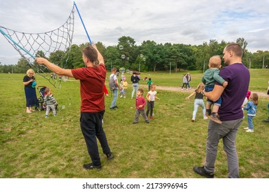 POZNAN, POLAND - Aug 29, 2021: A man creating large soap bubbles for a group of happy kids trying to catch them at Malta Park, Poland