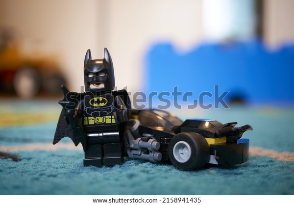 POZNAN, POLAND - Feb\
09, 2022: A closeup shot of a DC Comics Batman figure with\
Batmobile vehicle on a\
carpet