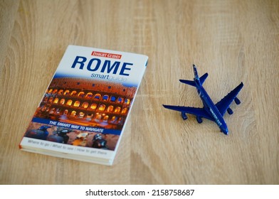 POZNAN, POLAND - Feb 20, 2022: A Rome Travel Guide Laying Next To A Toy Model Passenger Plane On A Table 