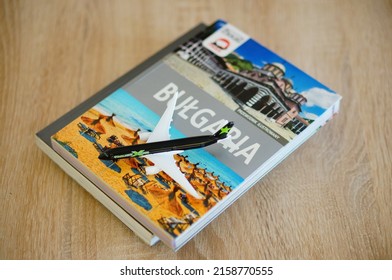 POZNAN, POLAND - Feb 20, 2022: A Toy Model Passenger Plane On A Travel Guide About Bulgaria On A Table 