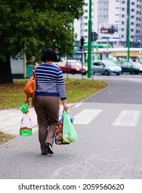 POZNAN, POLAND - Oct 18, 2015: A Woman Walking With Heavy Shopping Bags On A Sidewalk, Poznan, Poland