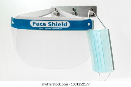 PPE Supplies Face Shield Direct Splash Protection And Mask Hanging On Hooks. New Clean Corona Virus Protective Equipment Ready To Use For Coronavirus Prevention.