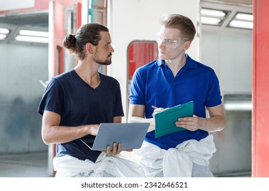 PPortrait Professional painters team wearing protective gear. Standing with a laptop and a notepad next to the car in front of the car paint shop. view work information Painter and car detailer - Powered by Shutterstock