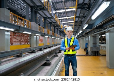 Pprofessional engineer worker hold tablet and look at camera with smiling also stand near railroad tracks in factory workplace.