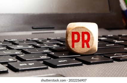 PR, Public Relations concept, wooden cube block with letters forming word PR on white gridline notebook, spread of information from organization to the public.