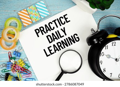 Practice Daily Learning text on a paper surrounded by office supplies, a magnifying glass, and a clock on a blue wooden surface
