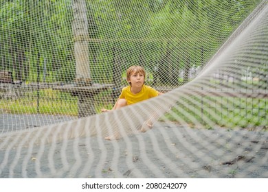 Practice Nets Playground. Boy Plays In The Playground Shielded With A Protective Safety Net. Concept Of Children On Line, Kid In Social Networks. Blurred Background, Blurred Motion Due To The Concept