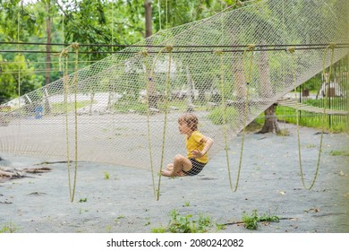 Practice Nets Playground. Boy Plays In The Playground Shielded With A Protective Safety Net. Concept Of Children On Line, Kid In Social Networks. Blurred Background, Blurred Motion Due To The Concept