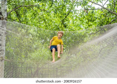 Practice Nets Playground. Boy Plays In The Playground Shielded With A Protective Safety Net. Concept Of Children On Line, Kid In Social Networks. Blurred Background, Blurred Motion Due To The Concept