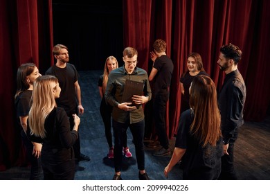 Practice in progress. Group of actors in dark colored clothes on rehearsal in the theater.