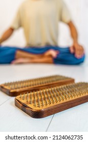 Practice of standing on nails. Closeup of wooden sadhu board with nails for sadhu practice. Man sitting in lotus position on the background.