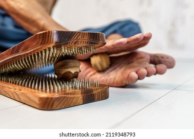 Practice of standing on nails. Sadhu wooden board with nails for sadhu practice. Man massaging his foot with a wooden massager after practicing standing on nails