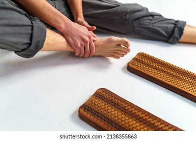 Practice of standing on nails. Sadhu wooden board with nails for sadhu practice. Close-up of a man massaging a foot with imprints from nails