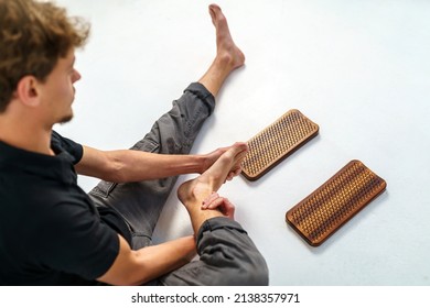 Practice of standing on nails. Sadhu wooden board with nails for sadhu practice. Man massaging a foot with imprints from nails