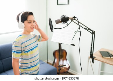 Practicing for my music lessons. Cute happy boy recording a song with a microphone for his singing classes 