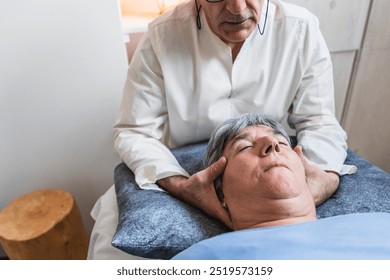 Practitioner focuses on head support during craniosacral therapy in a quiet, calm space. Concept of relaxation and energy flow for physical healing. - Powered by Shutterstock