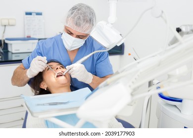 Practitioner male dentist drilling tooth to female patient in dental studio - Shutterstock ID 2039177903
