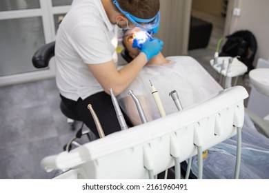 Practitioner Male Dentist Drilling Tooth To Patient In Dental Studio