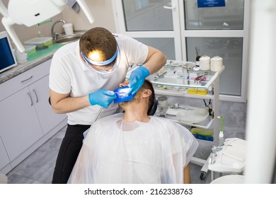 Practitioner Male Dentist Drilling Tooth To Patient In Dental Studio