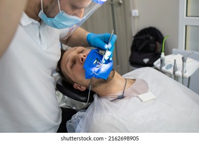 Practitioner Male Dentist Drilling Tooth To Patient In Dental Studio